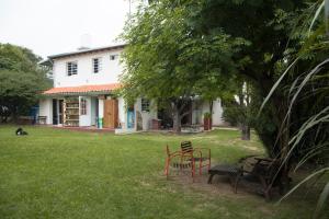 un patio con sillas y un banco frente a una casa en Feliza Hostel en Villa Carlos Paz
