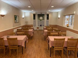 a dining room with tables and chairs with pink tablecloths at Belmont Hotel in Birmingham