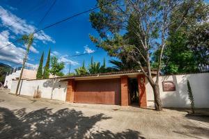 a building on the side of a street with a tree at Hotel Casa Yunenisa in Oaxaca City
