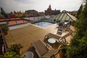 a deck with chairs and a swimming pool on a building at Estrella de Belem B&B and Spa in Cholula