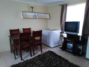 sala de estar con nevera, mesa y sillas en Casa de Campo A Pasos De La Ciudad en Punta Arenas