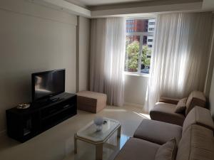 uma sala de estar com um sofá e uma televisão de ecrã plano em Av. Paulista Trianon MASP em São Paulo
