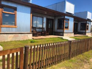 a house with a wooden fence in front of it at Patagonia Austral Suites - Cabaña con servicio de hotel - DESAYUNO INCLUIDO! in El Calafate