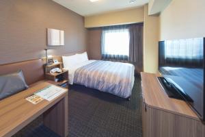 a hotel room with a bed and a flat screen tv at Hotel Route-inn Yamaguchi Yuda Onsen in Yamaguchi