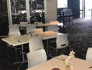 a dining room with white tables and white chairs at The Premier Hotel Broadmeadow in Newcastle