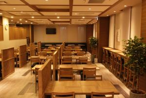 a restaurant with wooden tables and chairs in a room at Hotel Route-Inn Ishioka in Ishioka