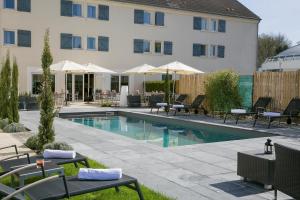 a swimming pool with tables and chairs next to a building at Hôtel Best Western The Wish Versailles in Guyancourt