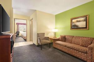 a hotel room with a couch and a television at Days Inn & Suites by Wyndham Thompson in Thompson