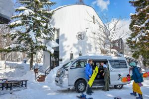 a group of people standing in the back of a van in the snow at Penke Panke Lodge and Apartments in Hakuba