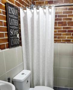 a white shower curtain in a bathroom with a toilet at Super Cute Hampton Suites in Imus