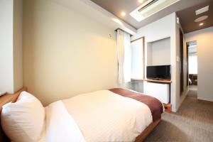 a bedroom with a bed and a flat screen tv at Posada Suimei in Hakone