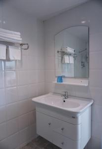 a white bathroom with a sink and a mirror at Lew Residence in Phayao