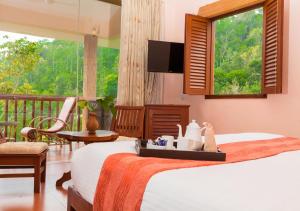 a bedroom with a bed and a balcony with a television at Oxygen Resorts Thekkady in Thekkady