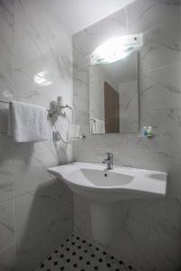 a white bathroom with a sink and a mirror at Piskin Hotel in Denizli