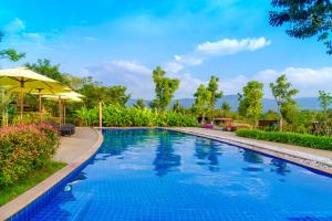 uma piscina com um guarda-sol ao lado de um resort em Limon Villa Khao Yai by Tolani em Wangkata