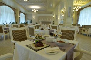 a dining room with white tables and white chairs at Sobi Hotel in Vyshhorod