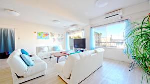 白濱的住宿－Shirahama White Beach House - Self Check-In Only，客厅配有两把白色椅子和电视
