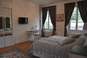 a bedroom with a bed and a desk and windows at Demeure Les Aiglons, Chambres d'hôtes & Spa in Fontainebleau