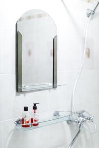 een wastafel in de badkamer met een spiegel en 2 flessen op een plank bij Квартира в самом центре Тулы in Tula
