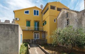 una casa amarilla con ventanas azules y una valla en Apartment DIANA - Great Location, Cosy 2 Bedroom, 2 Bathroom apt, en Kukljica