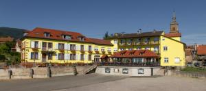 ein gelbes Gebäude mit einem Uhrturm in einer Stadt in der Unterkunft Relais du Klevener in Heiligenstein