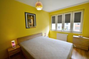 a yellow bedroom with a bed and two windows at ApartamentyPrzyMorzu Zielone Tarasy in Kołobrzeg