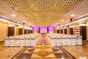 a large banquet hall with rows of tables and chairs at Hotel Fun City in Navsāri