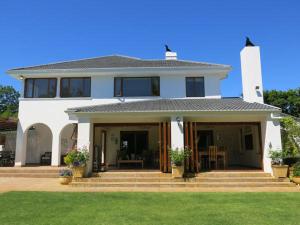 a white house with a porch and a lawn at Oakvale Lodge in Cape Town