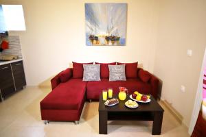 a red couch in a living room with a table at Luna Bianca - Corfu Apartments in Corfu Town