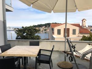 a table and chairs on a balcony with an umbrella at Apartments Montevideo in Mali Lošinj