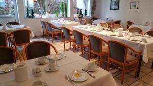 een eetkamer met tafels en stoelen met witte tafelkleden bij Hotel Walz in Salzkotten