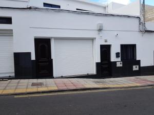 a white building with three garage doors on a street at La Vega de Mary in Arrecife