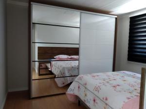 1 dormitorio con armario con espejo y cama en moradia garden village, en Balneário Camboriú