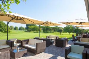 eine Terrasse mit Stühlen, Tischen und Sonnenschirmen in der Unterkunft Hotel Golf Inn in Lignano Sabbiadoro
