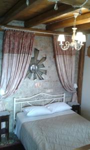 a bedroom with a bed with curtains and a chandelier at To Stolidi tis Psinthou in Psinthos