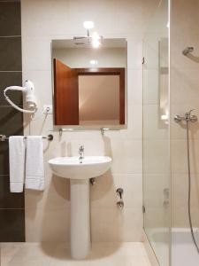 W łazience znajduje się umywalka, prysznic i lustro. w obiekcie Residencial Coroa D'Ouro w Fatimie