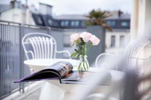 un vaso di fiori e un libro su un tavolo di Hôtel De Sers Champs Elysées Paris a Parigi