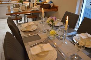 a dining room table with candles and plates and chairs at The Captains Cottage, Cushendall in Cushendall