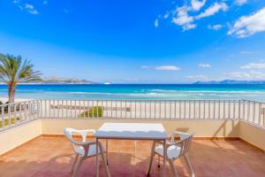 balcón con mesa, sillas y vistas al océano en Beachfront Villa Socias Playa en Playa de Muro