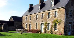 蓬托尔松La Vieille Foulonnière : Chambres d'hôtes & Permaculture的一座大砖砌建筑,在院子里设有桌子