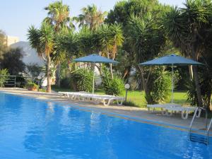 a swimming pool with tables and umbrellas in a resort at Apartments Seagull in Kos