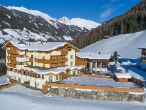 a large building in the snow with mountains in the background at Gasthof Tannen - Alm in Stummerberg