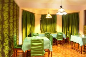 a dining room with green curtains and tables and chairs at Hotel Paradiso in Kalimpong
