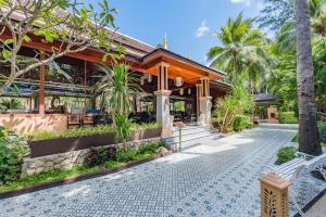 ein Haus mit einer Bank davor in der Unterkunft Princess Kamala Beachfront Hotel - SHA Extra Plus in Kamala Beach