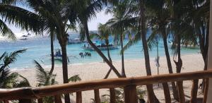 a beach with palm trees and boats in the water at DiveGurus Boracay Beach Resort in Boracay