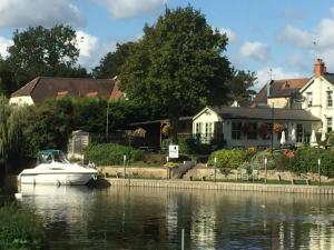 un barco en el agua frente a una casa en Old Beams Bed & Breakfast en Alcester