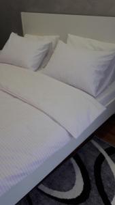 a bed with white sheets and pillows on it at Однокомнатная квартира-студия. Новострой, центр города. in Lutsk