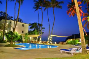 a resort with a pool and palm trees at night at O Pescador an Indy Resort in Panaji