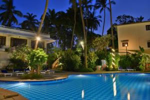 a swimming pool in front of a house at night at O Pescador an Indy Resort in Panaji