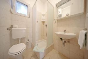 a white bathroom with a toilet and a sink at Apartmani Nada Super in Petrcane